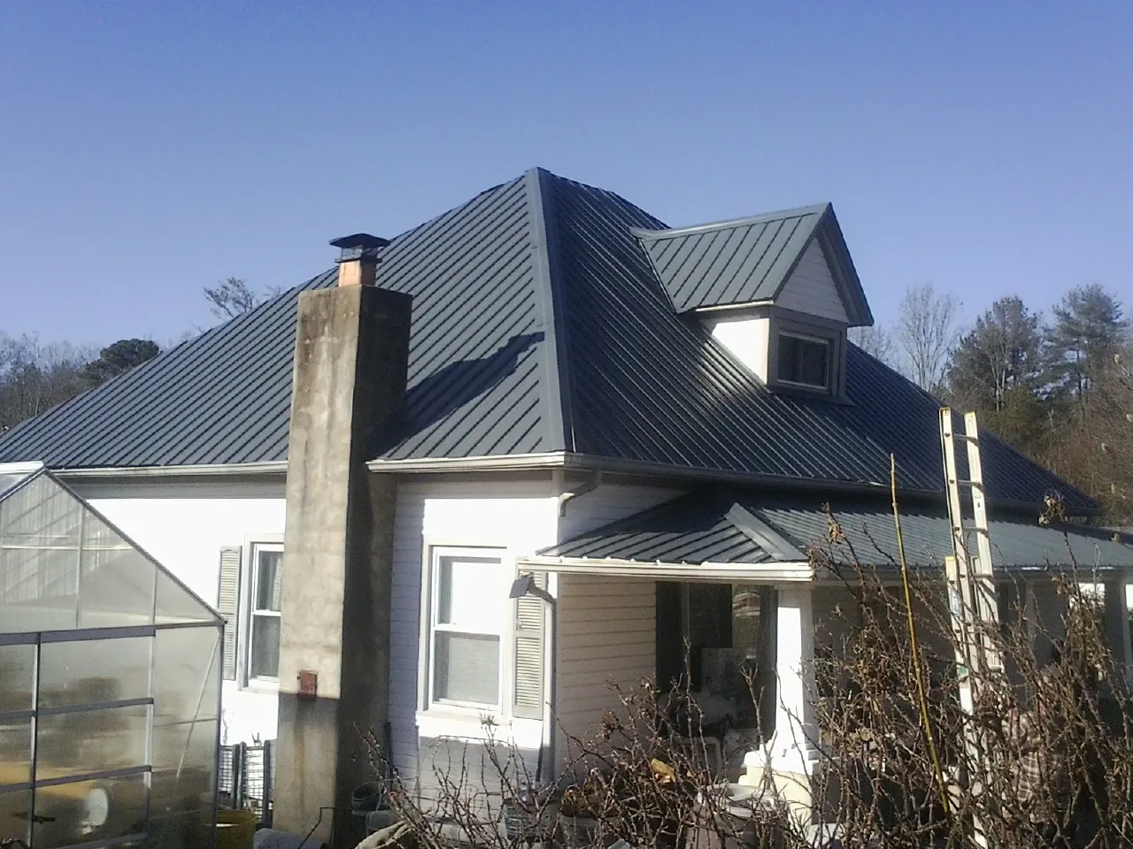Dark blue standing seam metal roof on a white farmhouse with dormer — Slate & Tile Roof Repair by Roofing Brothers in North Branch
