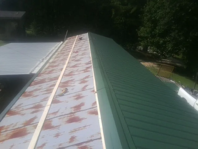 Old rusted panels beside newly installed green metal roofing — Wind Damage Roof Repair by Roofing Brothers in North Branch