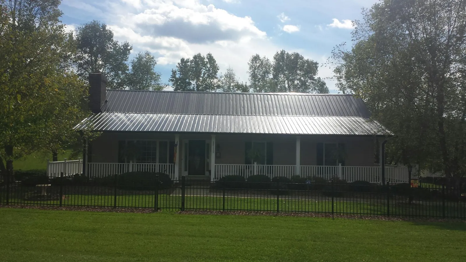 Gray metal roof on a brick ranch with a full width front porch — Gutter Guard Installation work by our crew in North Branch
