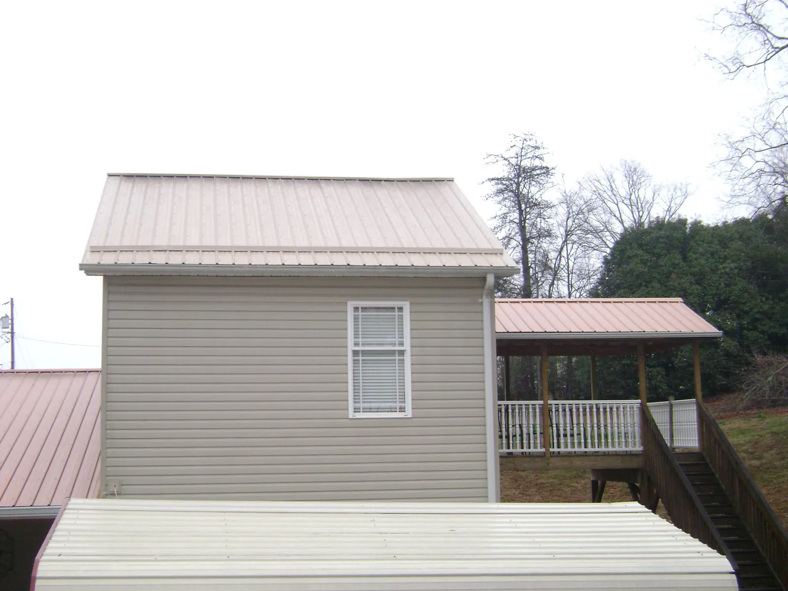 Tan metal roofs on a two story addition and attached porch, from a Roof Replacement job in North Branch