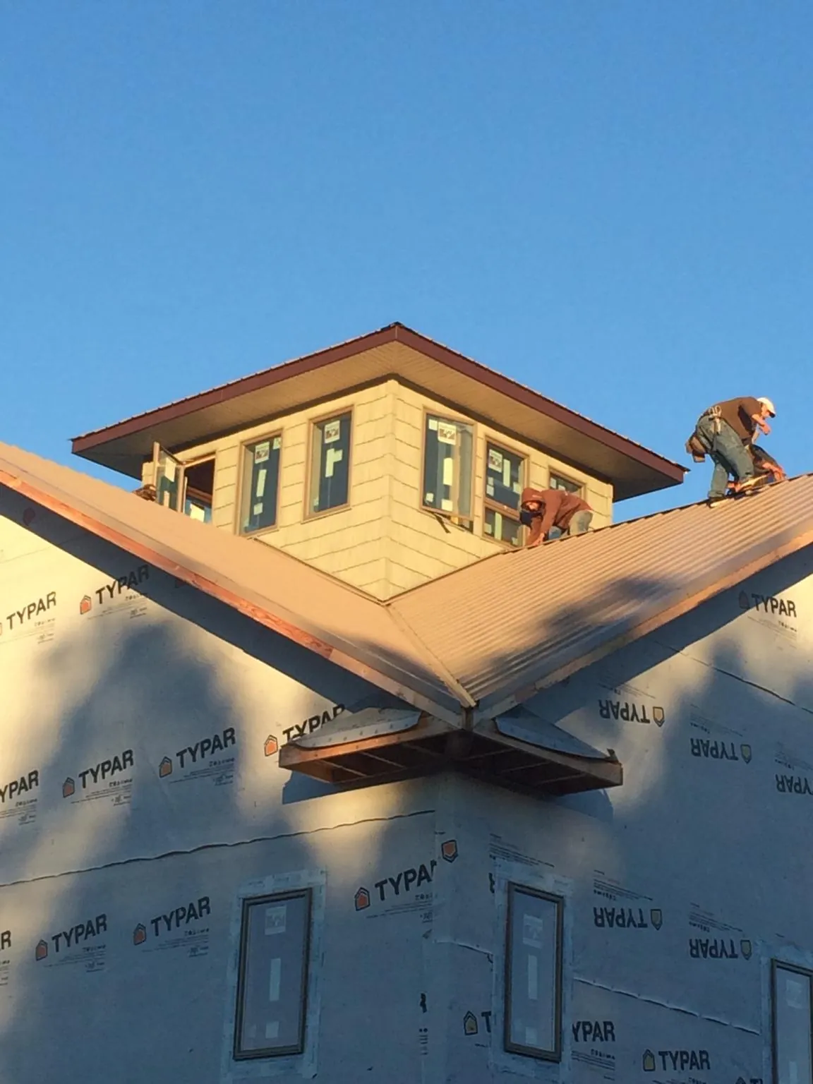 Roofers working around a rooftop cupola on a new metal roof at sunset — Roof Waterproofing in North Branch by Roofing Brothers